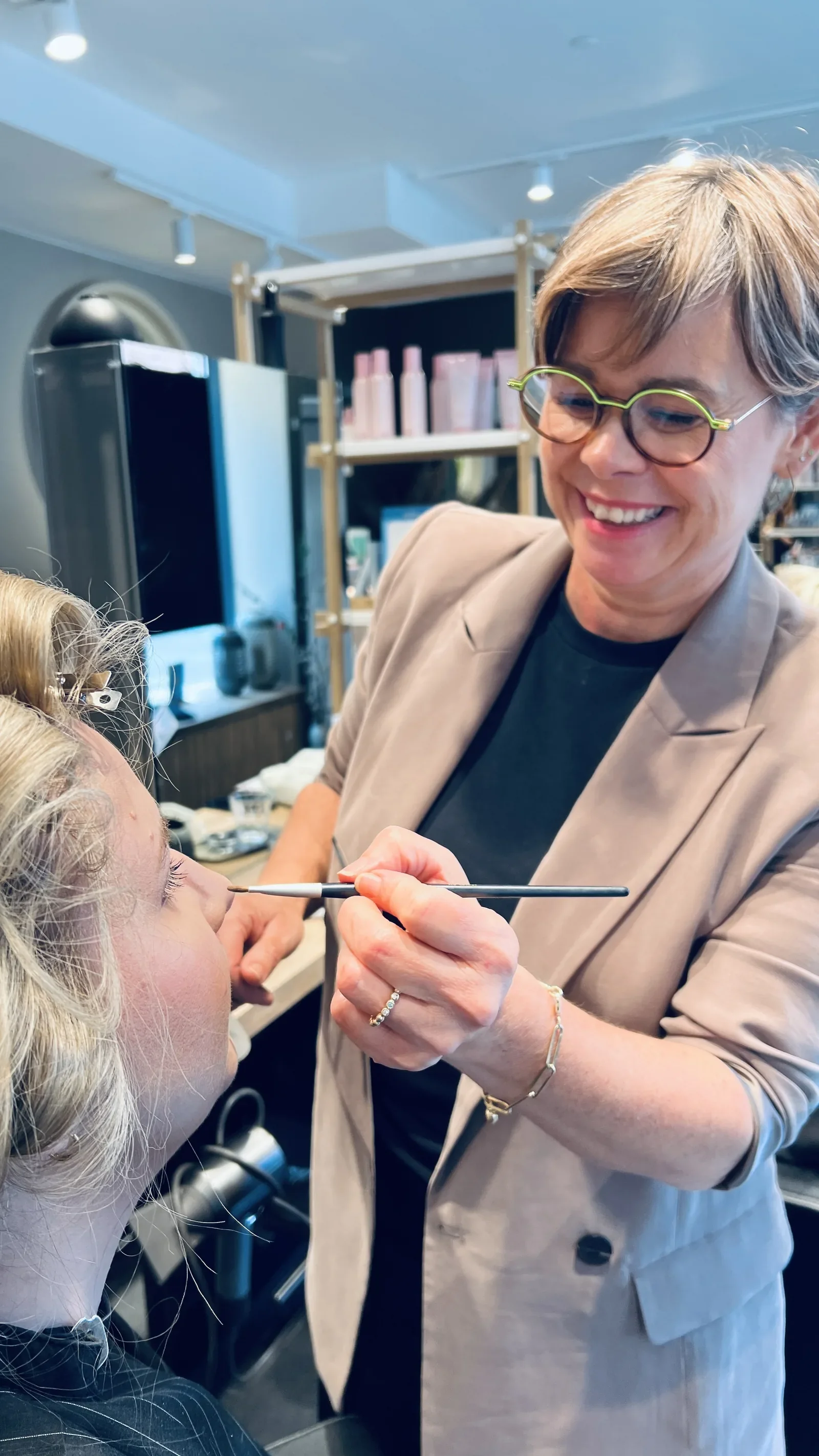 frisør og brudestylist lægger sidste hånd på brudemakeuppen