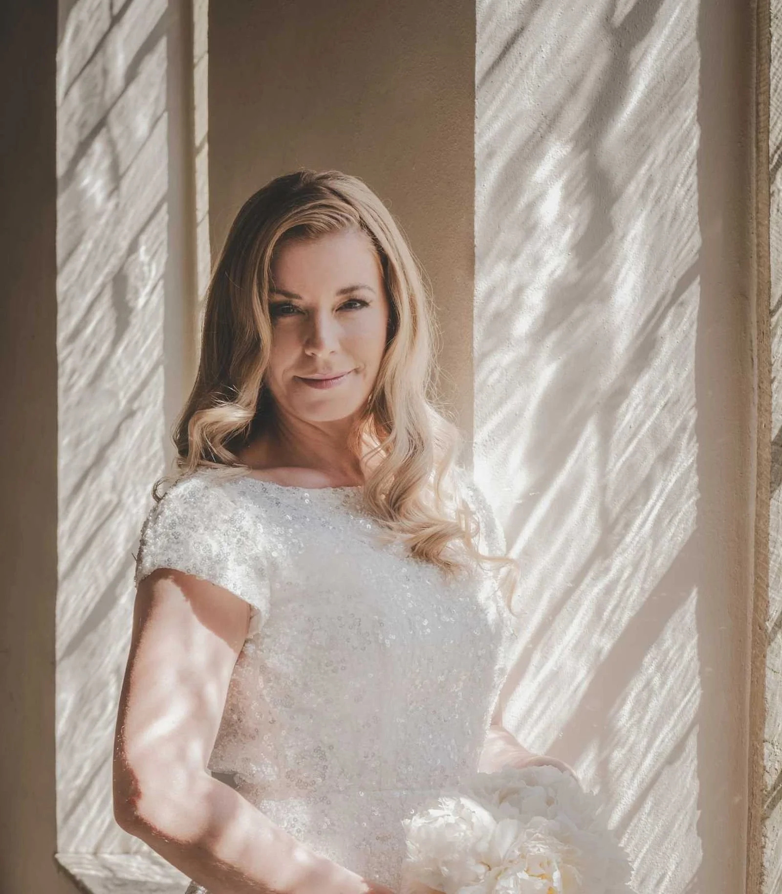 Brud i naturligt bryllupslook med bløde krøller og brudekjole, stylet af en professionel bridal stylist fra RiiStyle.