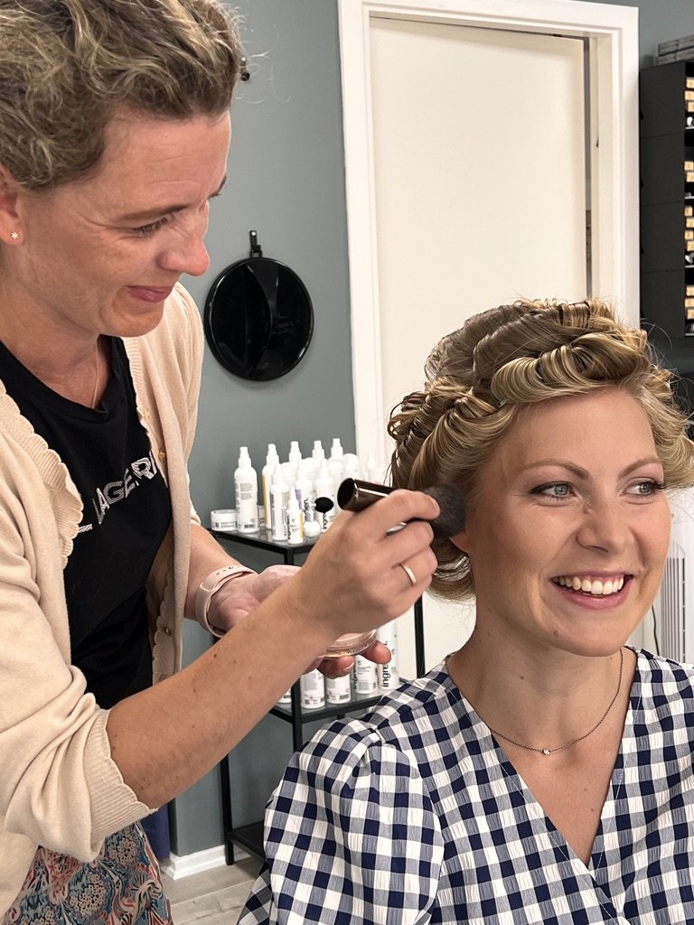 Britt lægger makeup på en smilende og glad brud