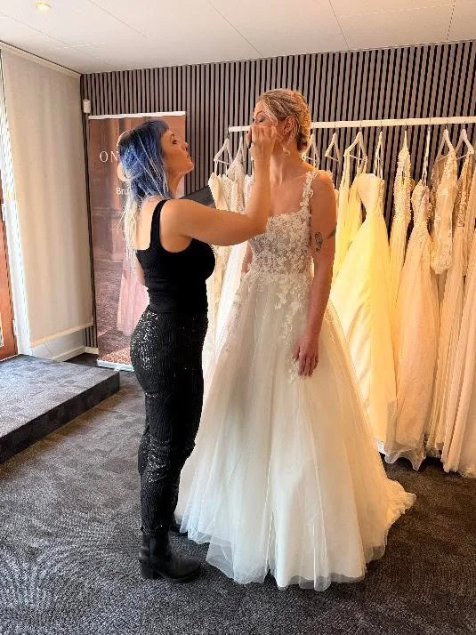 frisør og makeupartis retter brude makeuppen på brud i brudekjolebutik