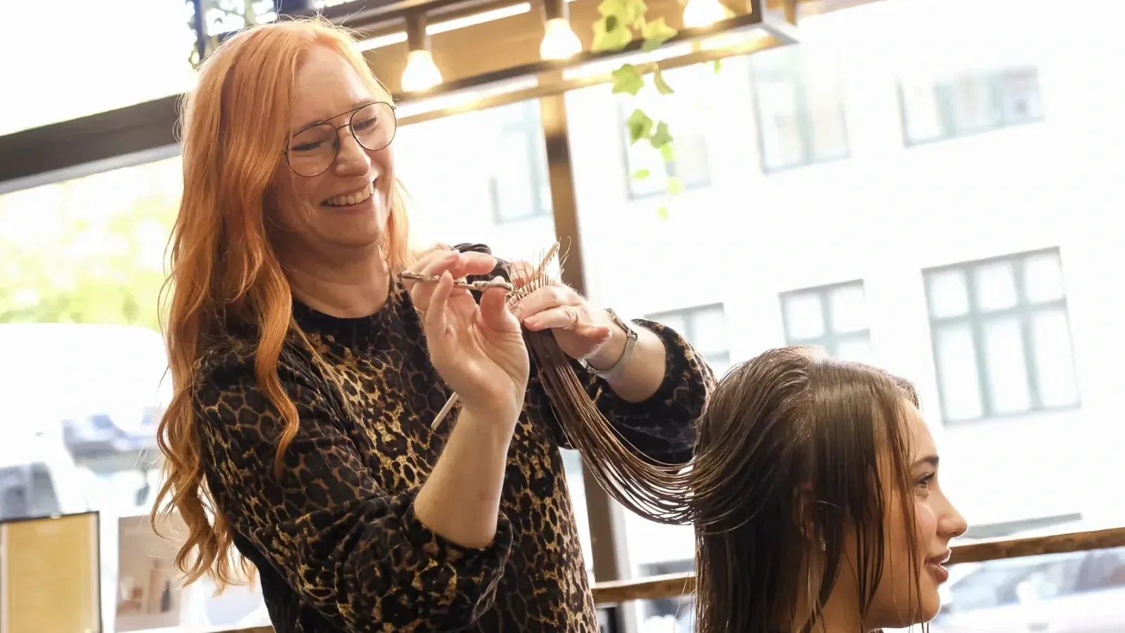 arbejdsbillede af Helle igang med at klippe spidser på langhåret kunde i stolen