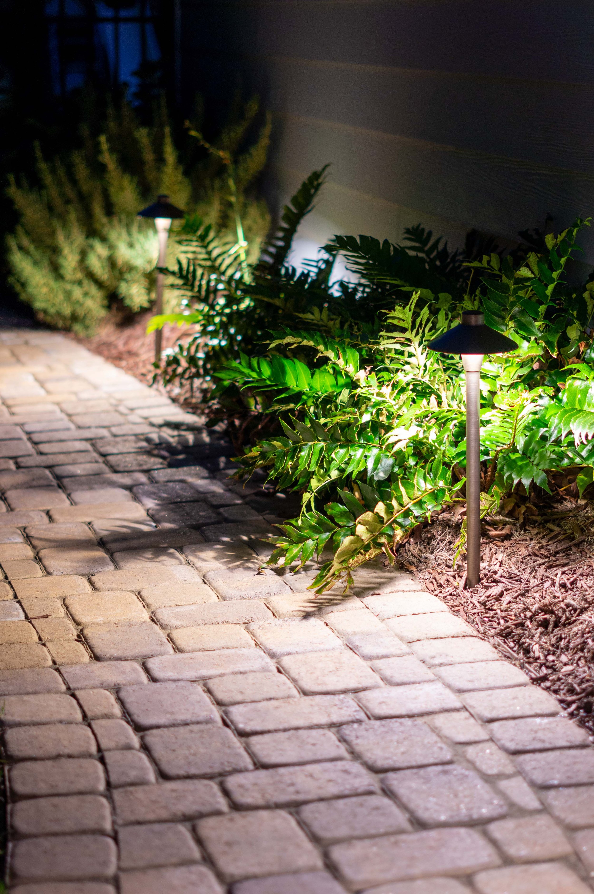  Path lights illuminating a stamped concrete pathway with a landscaped edge.  