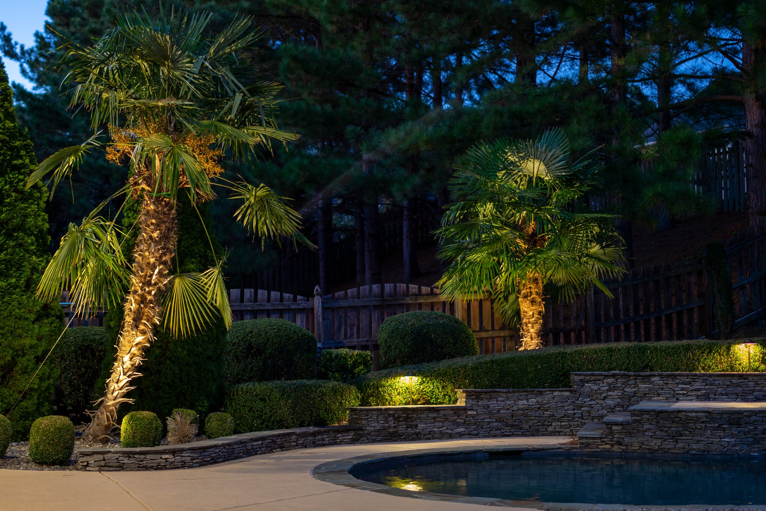  Landscaped poolside area with small stair stepped retaining wall accented with landscape lighting and path lights.  