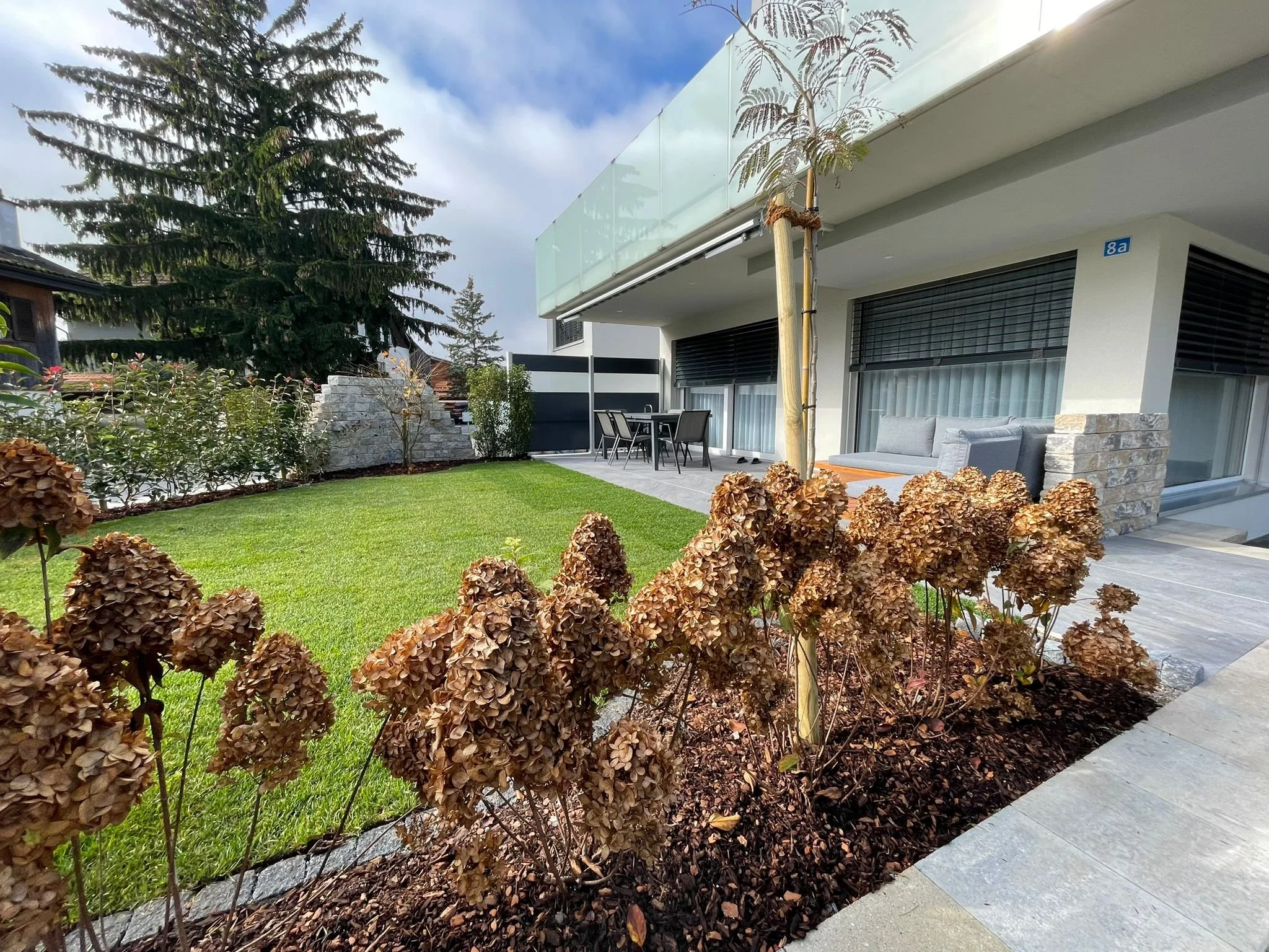 Gartengestaltung mit Rasen, Steinmauer und Terrasse – Projekt von Köhn Gartenbau AG im Rheintal