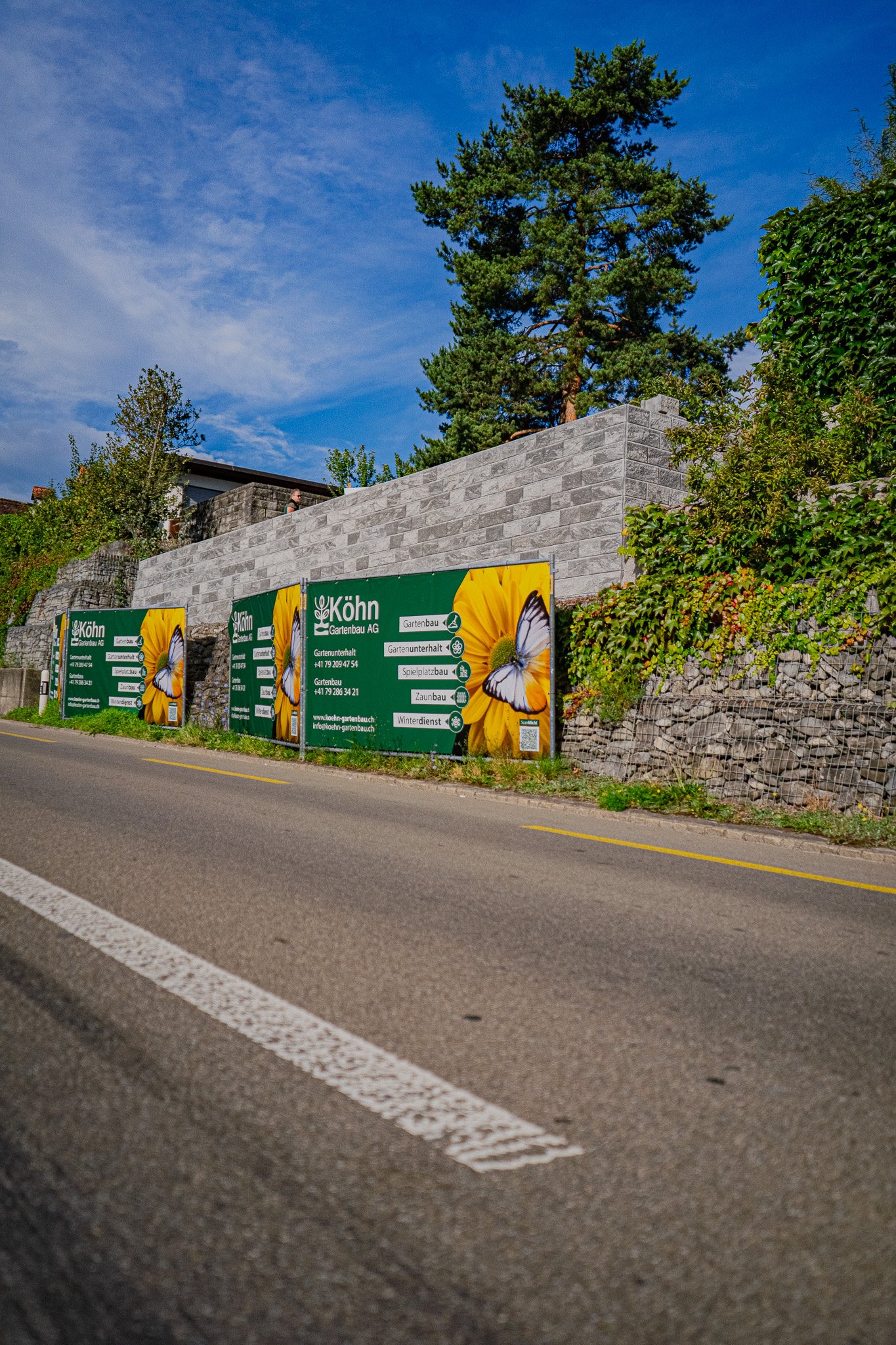 Köhn Gartenbau AG Firmensitz in Balgach mit Werbebanner an Steinmauer