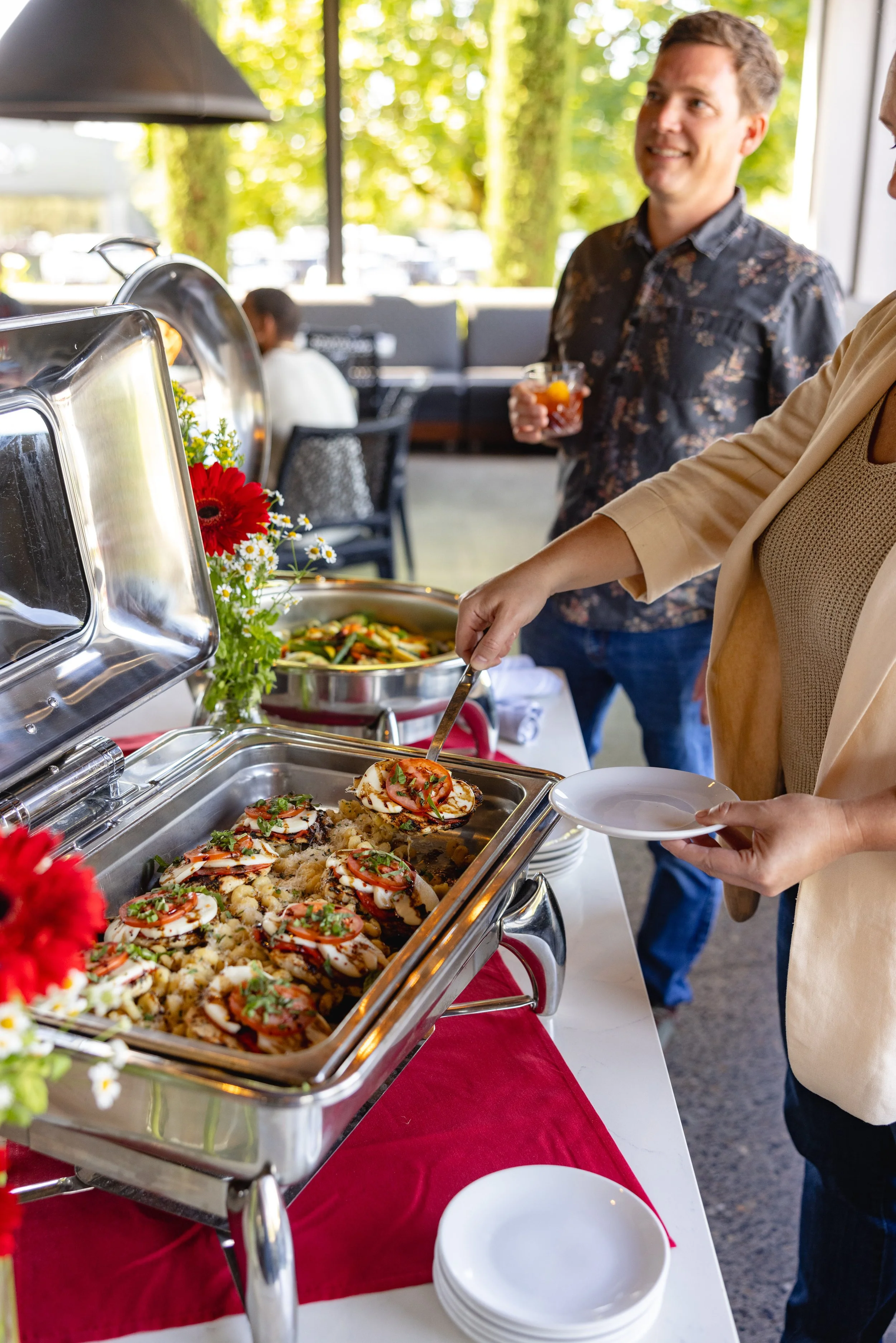 Guest serving plated appetizers from a catered buffet with fresh, chef-prepared dishes, highlighting convenient catering options for home or office gatherings.
