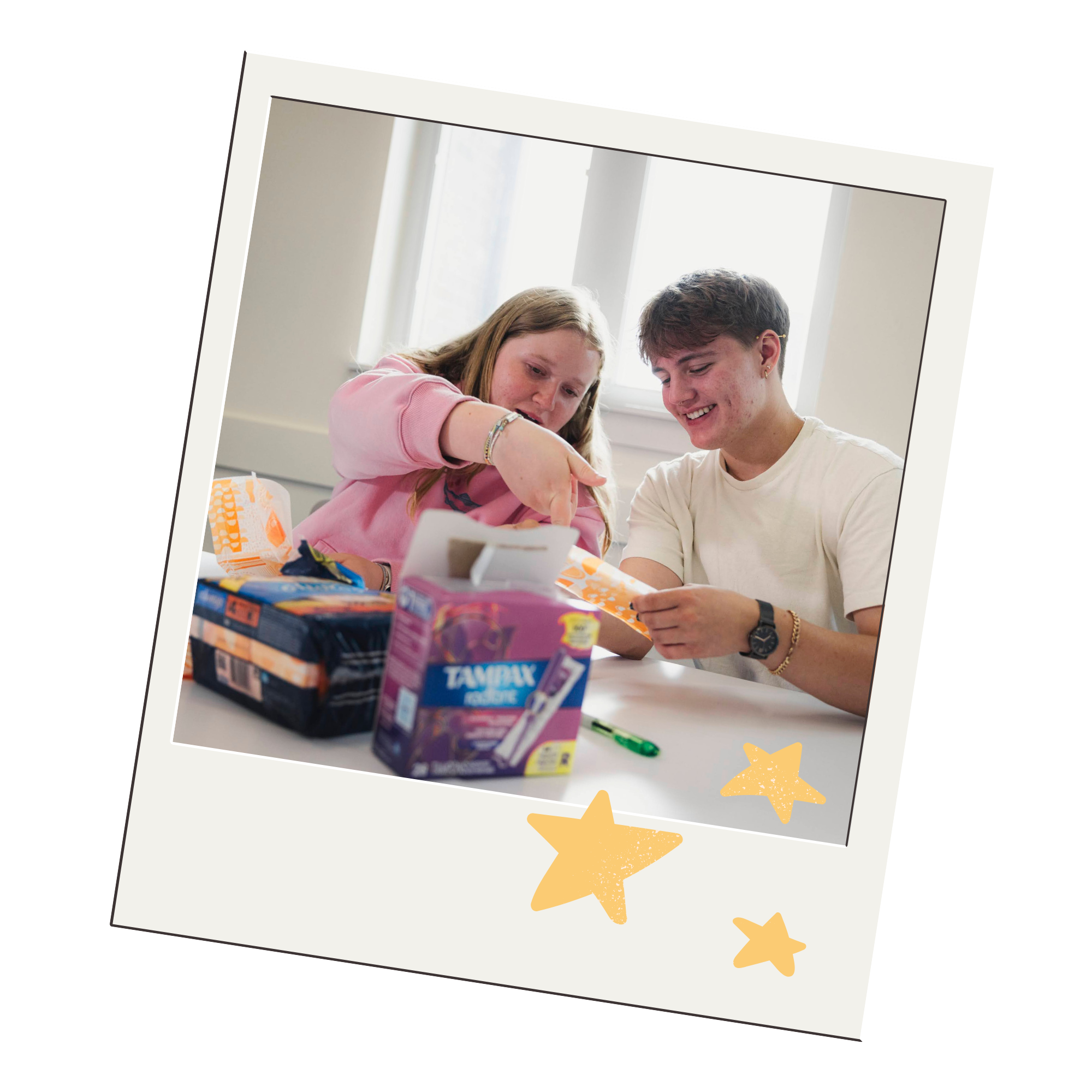 Two teens smile as they look at menstrual care products.