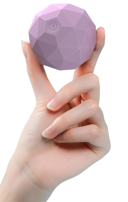 A hand holding a small, purple, geometric-shaped portable device with a power button icon on it.