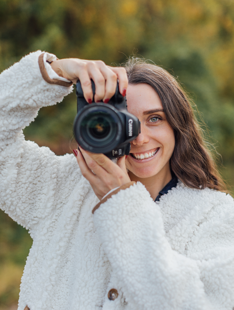 Photographer holding camera up to lens with half of face visible