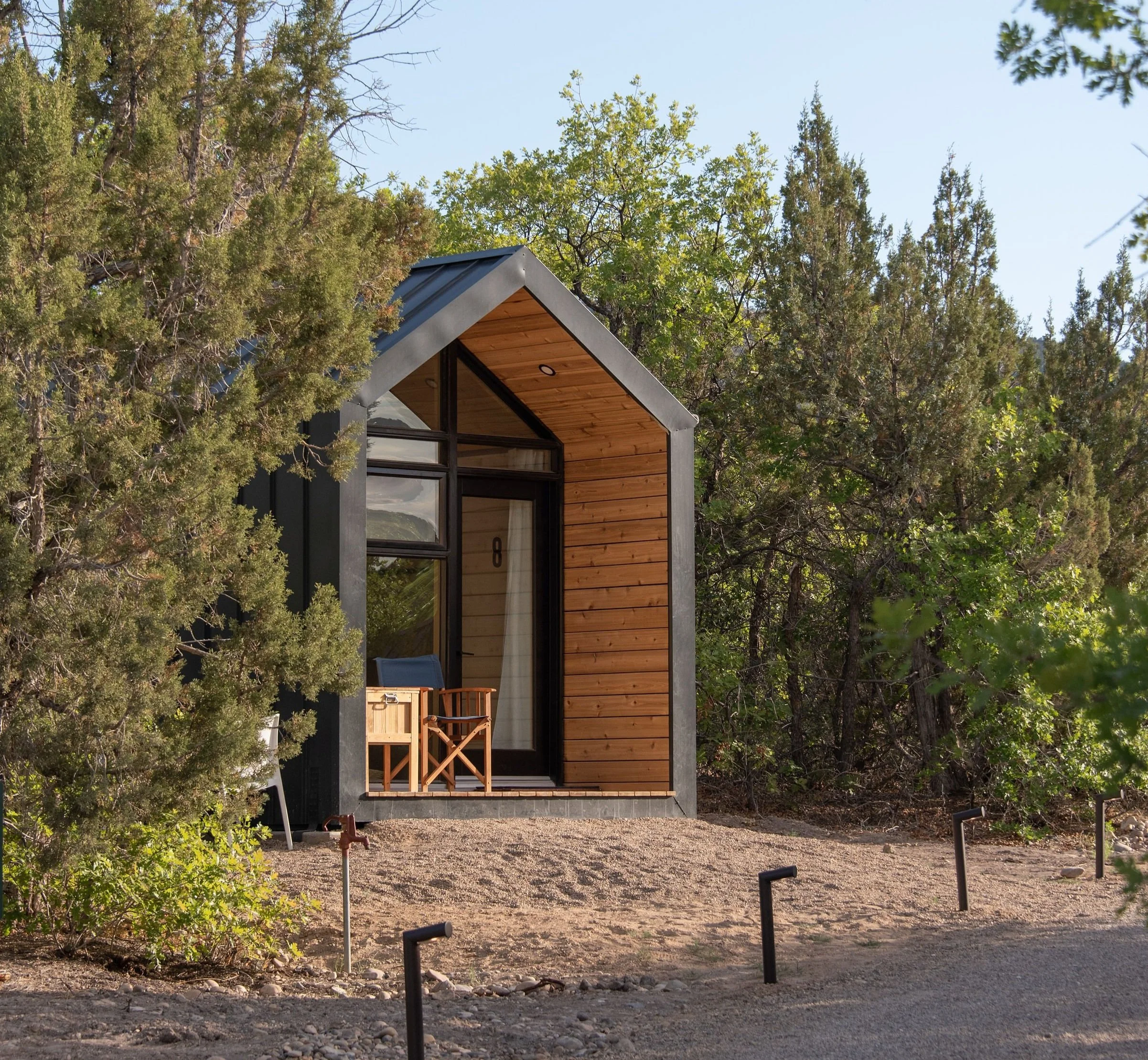 Tiny Cabin - Small modern cabin with wooden siding and large glass windows, surrounded by trees.