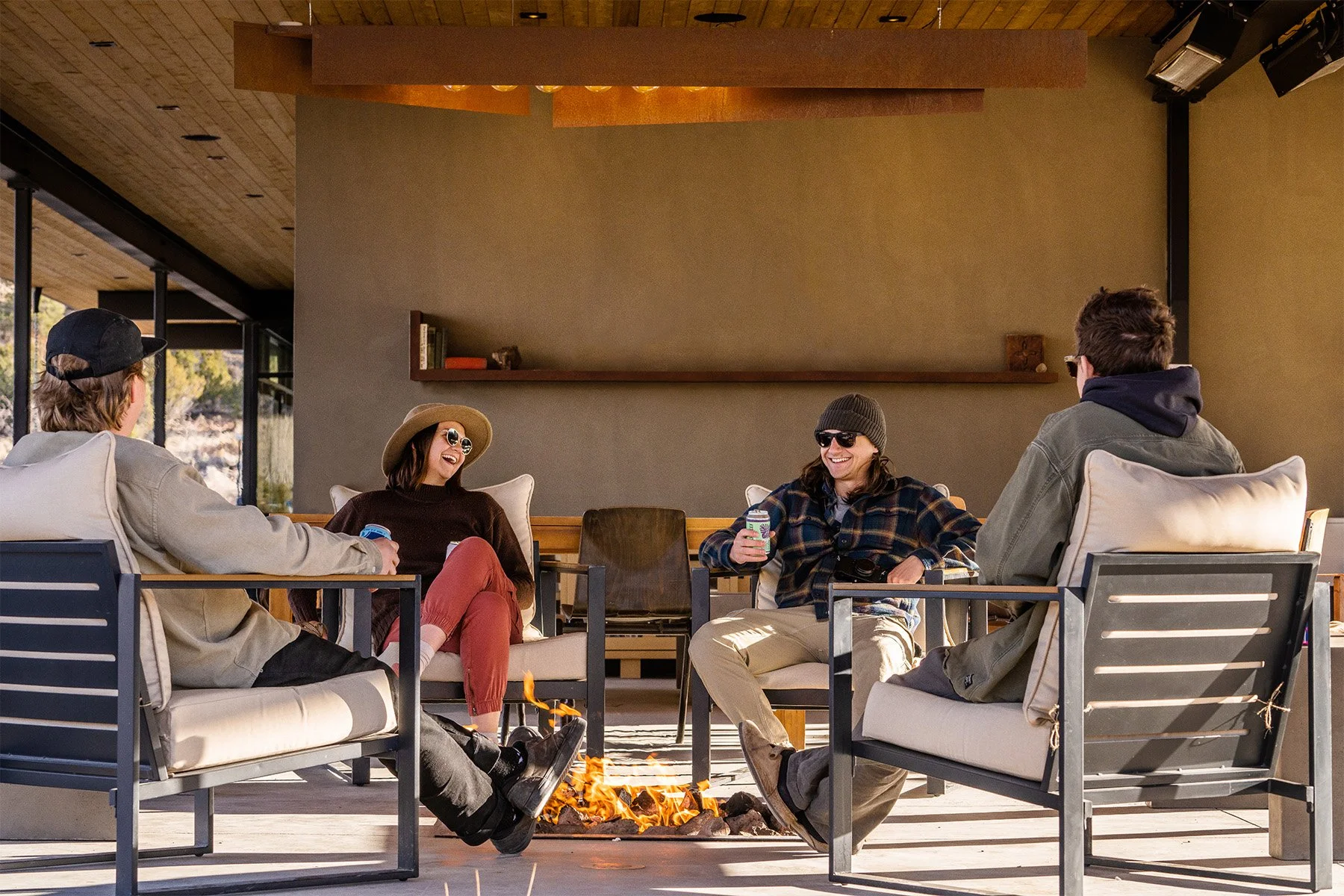 Group of people sitting and laughing around a fir pit at the Outdoor Lodge
