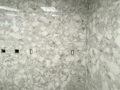 Remodled bathroom with marble tile walls with four rectangular cutouts.