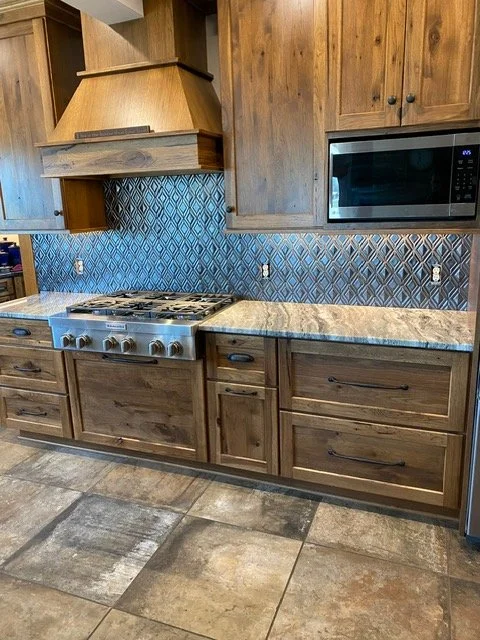 Remodeled kitchen with wooden cabinets, granite countertops, a stainless steel stove, and a microwave. Blue diamond-patterned tile backsplash and tiled floor.