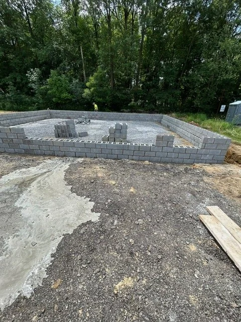 A foundation for a building under construction, with cinder blocks forming the perimeter walls on a gravel base