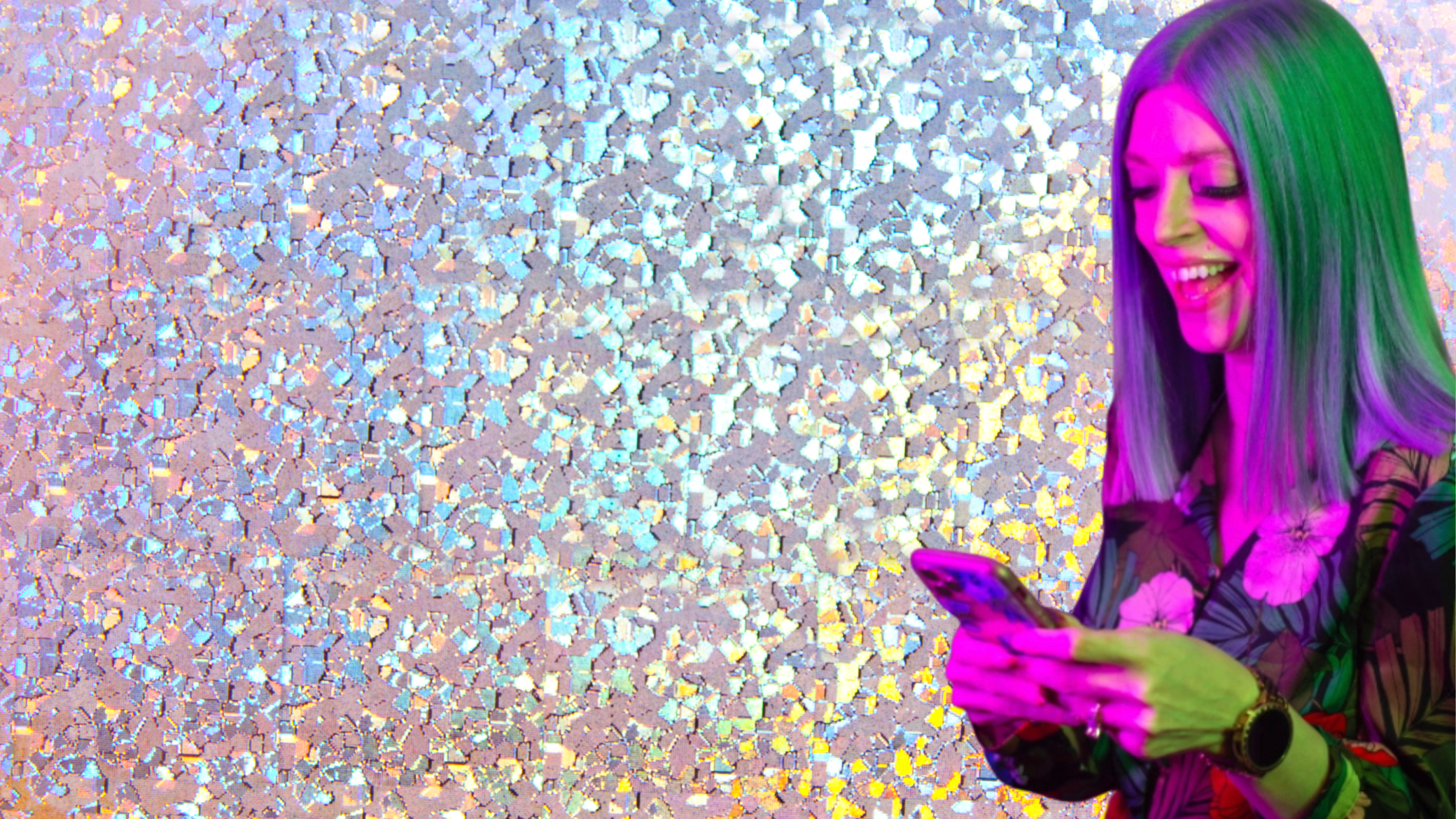 jhh is looking down at her phone and smiling. fun glitter background.