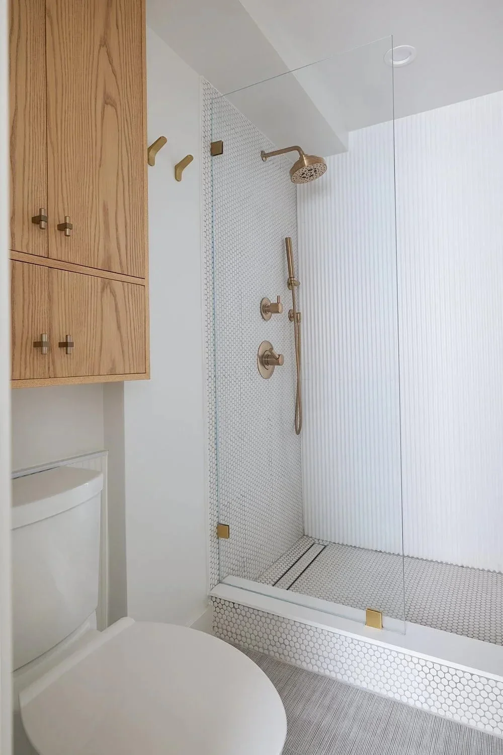 Wellness bathroom penny tile brass shower oak cabinet.webp