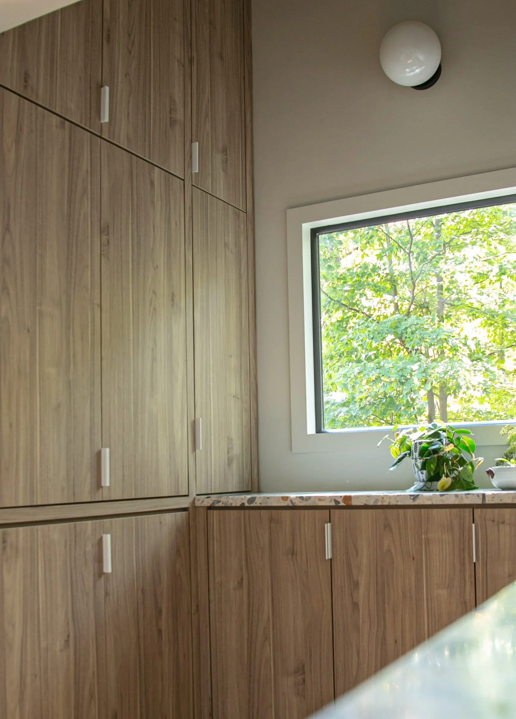 Natural wood kitchen cabinetry terrazzo countertop garden view.webp