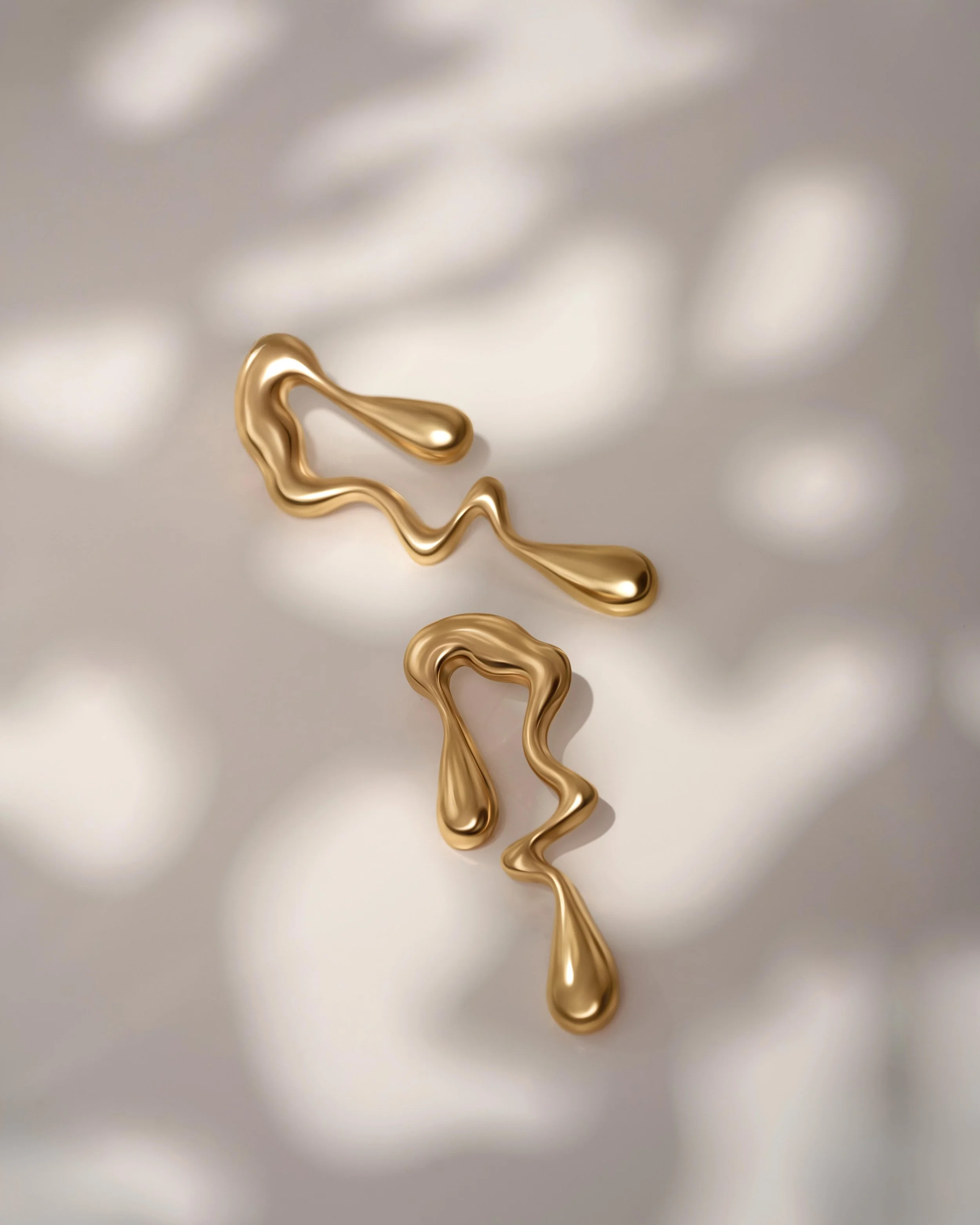 Professional jewellery product photography in London of unique gold earrings with organic shapes, styled on a neutral background