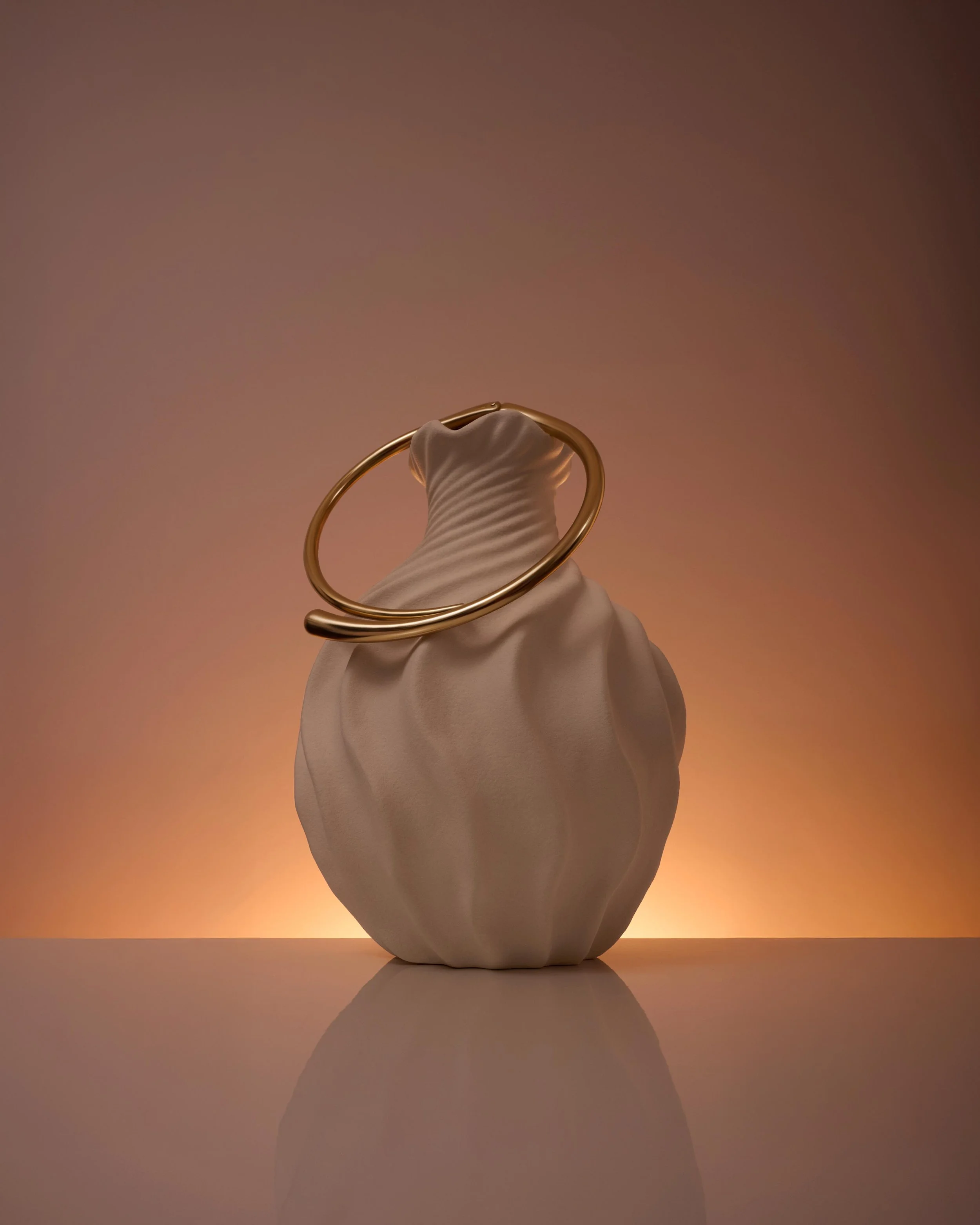 Luxury jewellery photography in London of a minimalist gold bangle styled on a sculptural ceramic vase with warm studio lighting