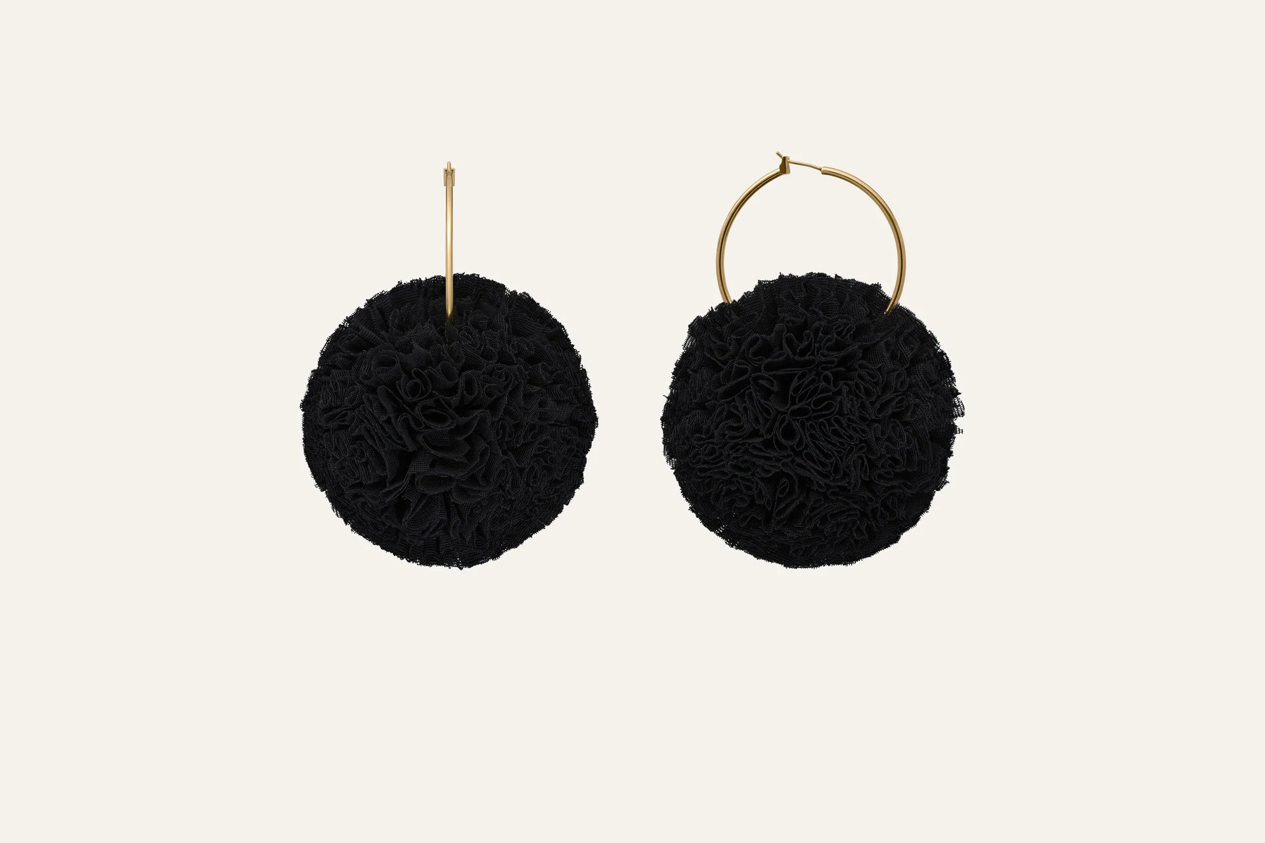 Pair of black textured spherical earrings with gold hooks, displayed against a plain cream background. Jewellery packshot