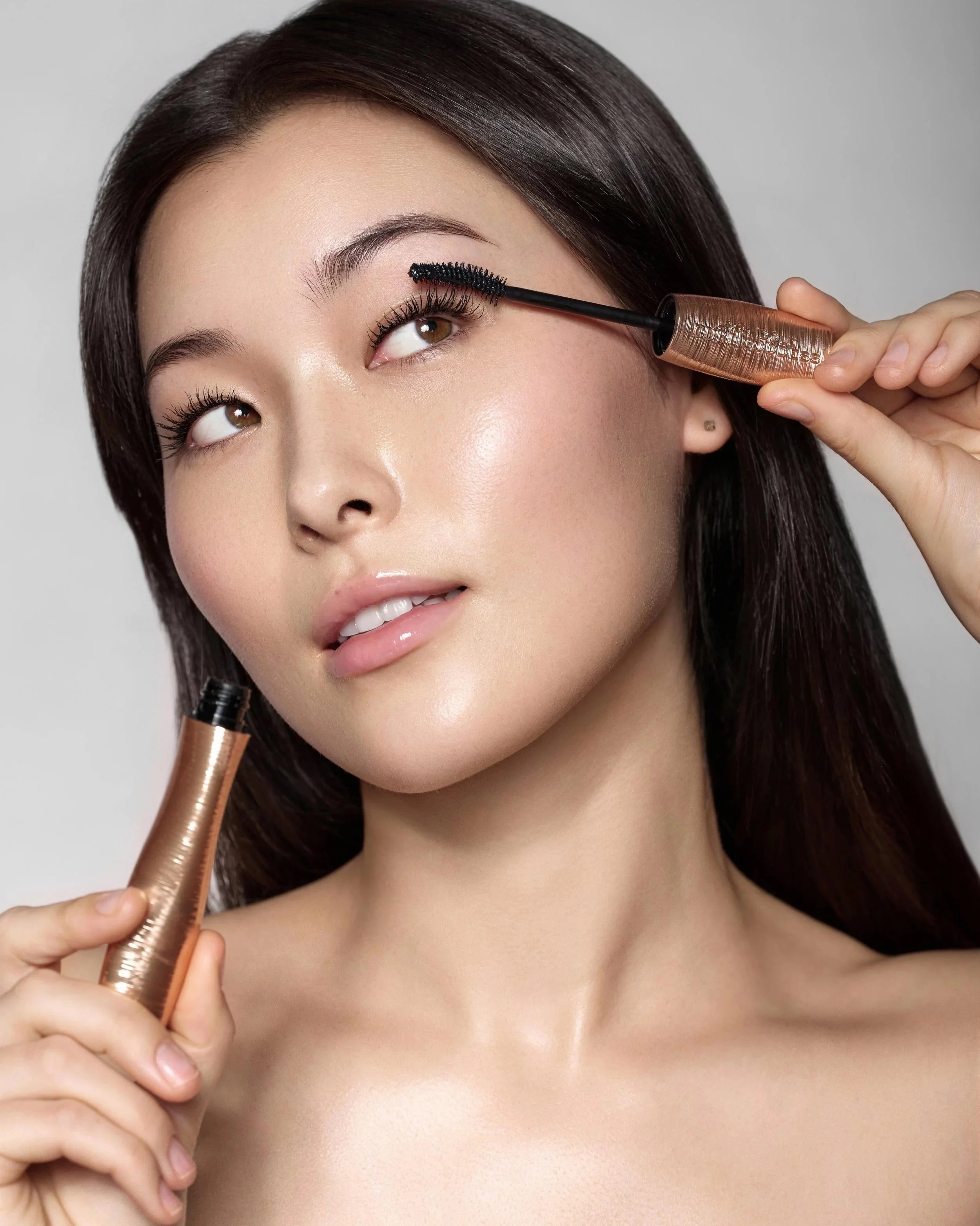 Beauty portrait of a model applying eye makeup with Lancome mascara, studio beauty photography
