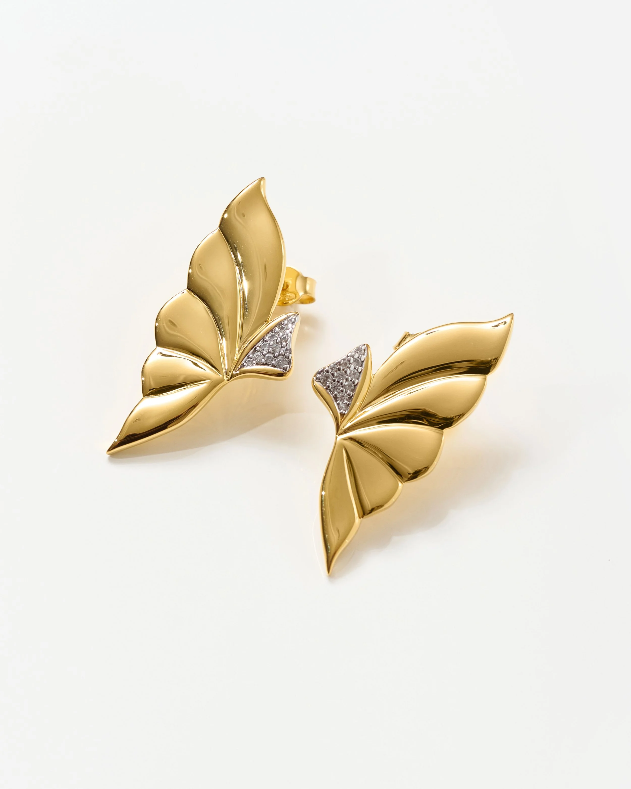 Gold butterfly-shaped brooch with diamond accents on a white background. Jewellery packshot photography