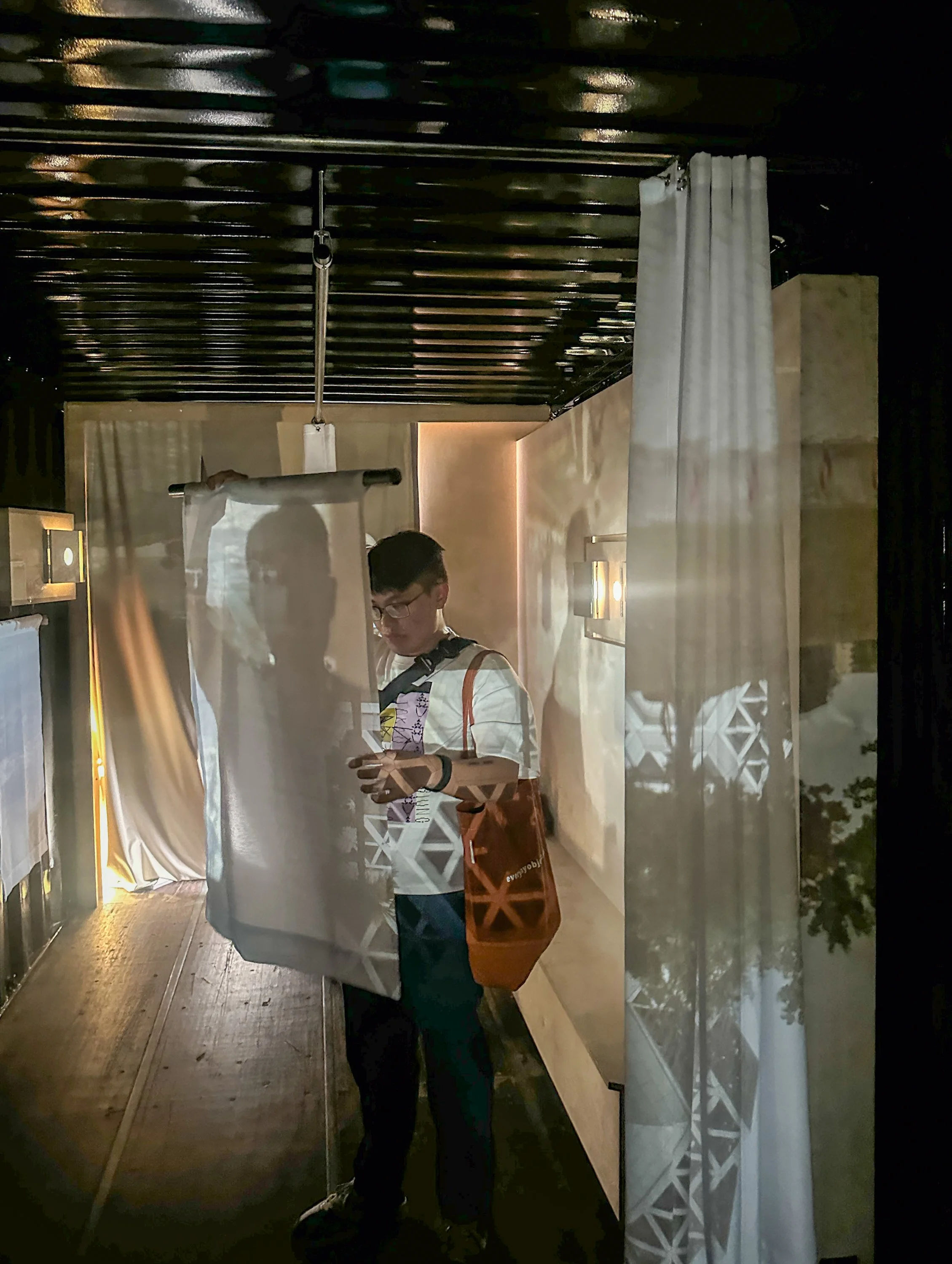 Interior view with an audience member in the center holding up a small portable screen, moving it around the space to find unique constellations. The projections are also visible on the audience members' colored clothing.