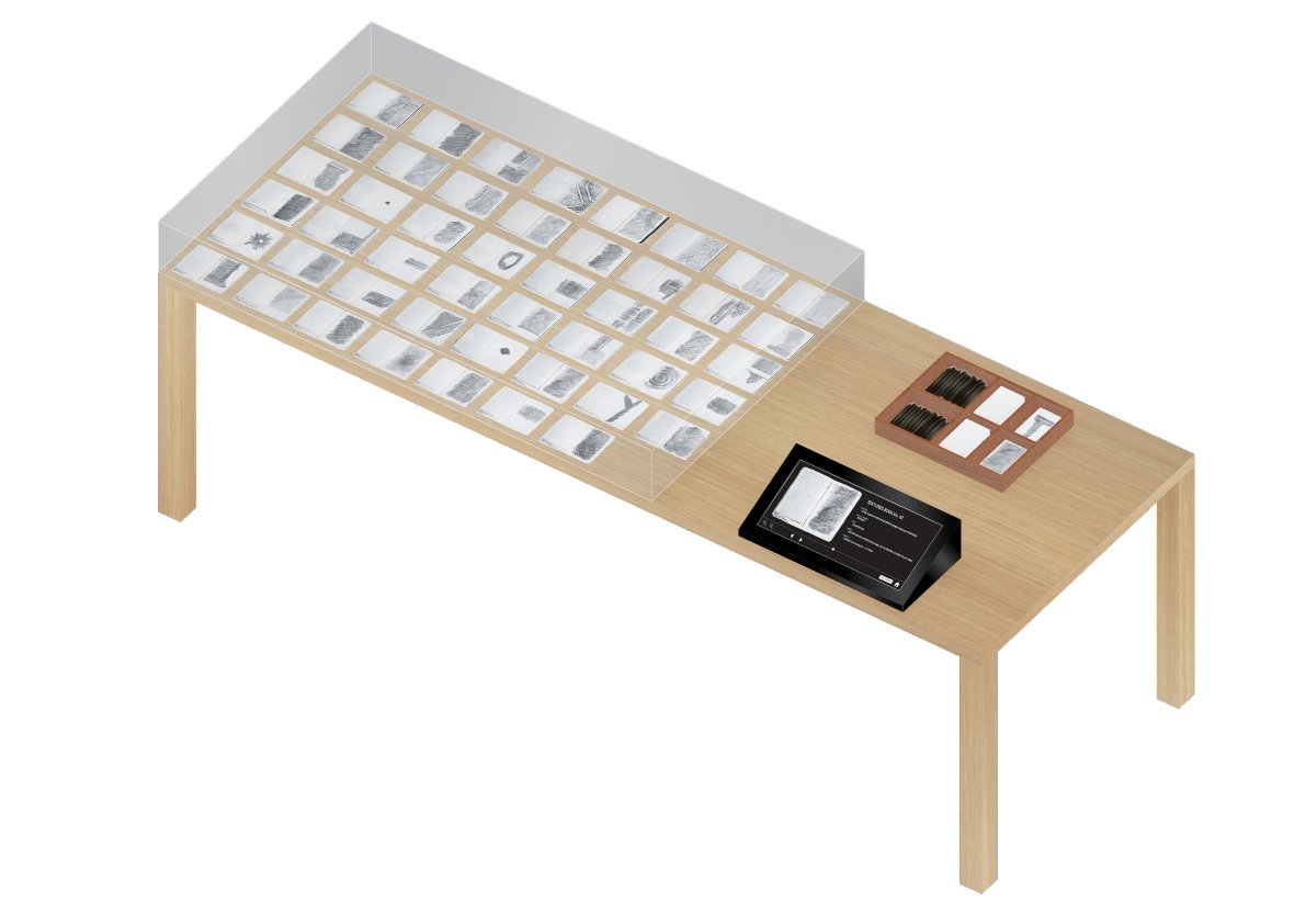 AXO drawing that shows how the textures can be displayed. The books are opened on a table, next to them is a digital screen where you can flip through all texture books, and a box with tools to make your own texture, and tactile textures to be felt.