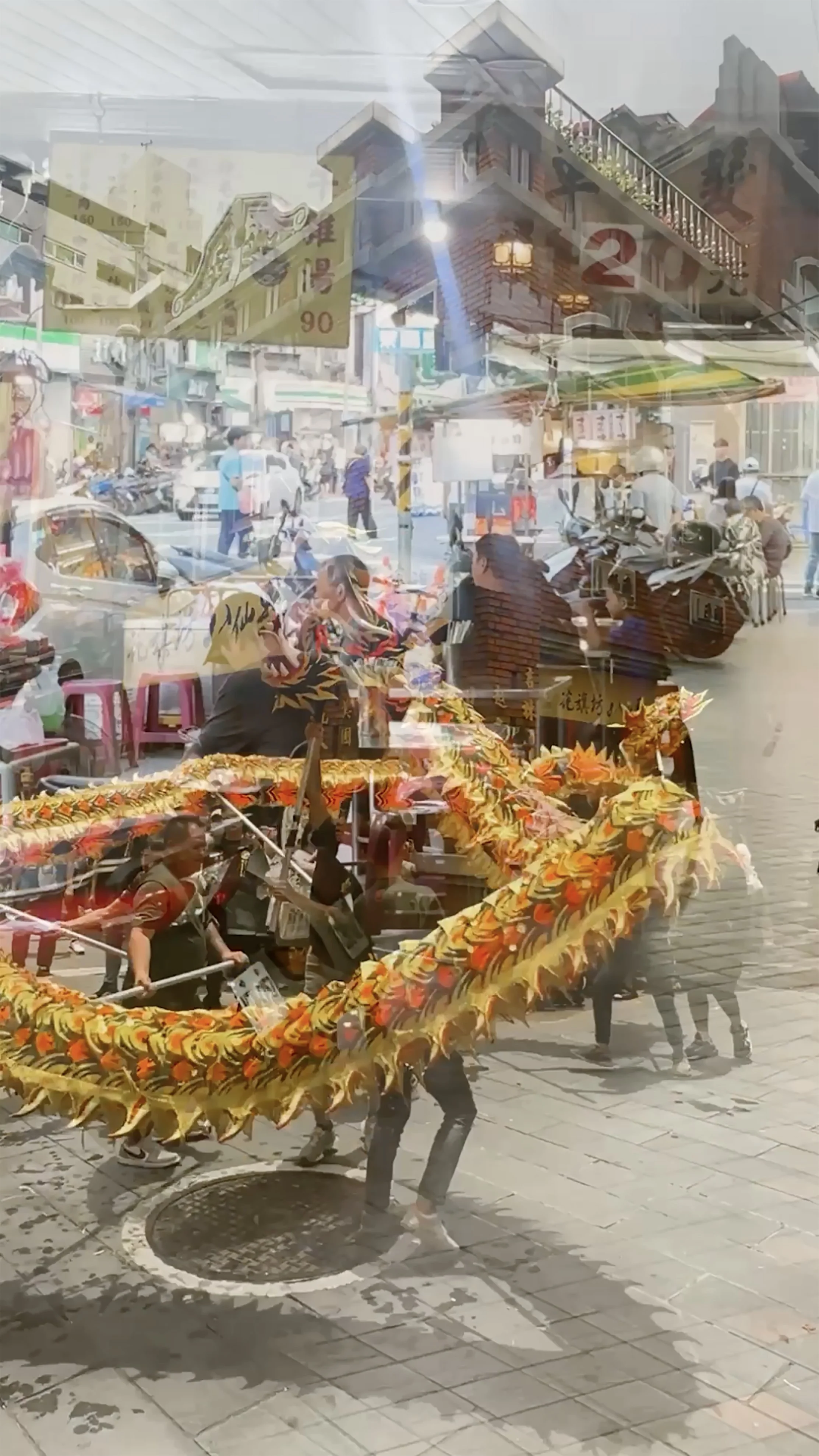 Screenshot from the film. Two scenes are merging: one of a dragon dance in front of a temple, the other of people having dinner on a covered sidewalk. By Troels Steenholdt Heiredal