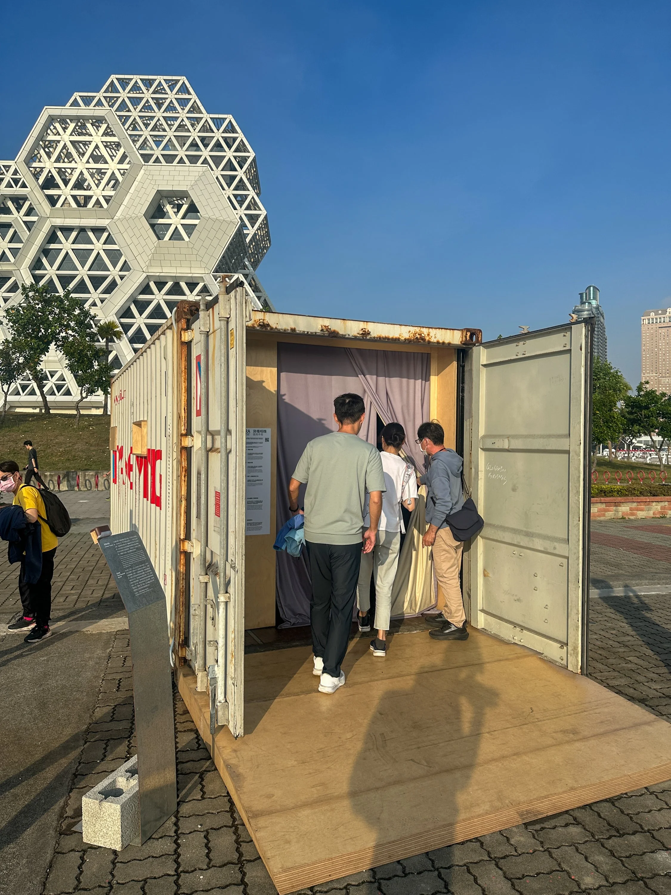 Image Description: View of the entrance of the Container Camera, where three people are entering the space through the fabric entrance. By Autistic architect and artist, Troels Steenholdt Heiredal