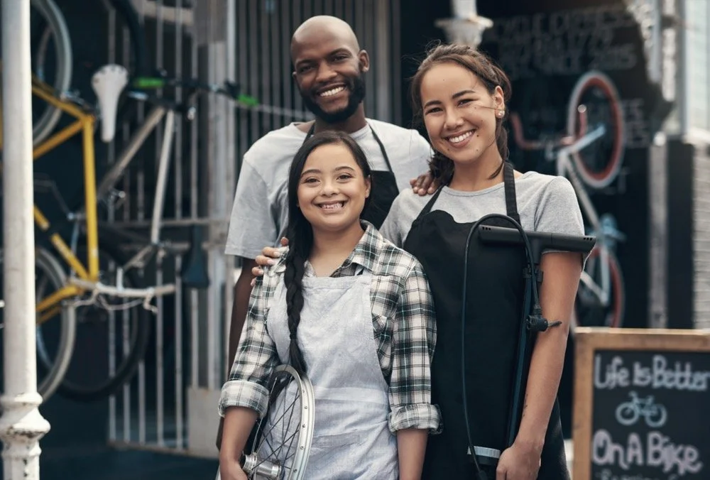 Family-owned bicycle shop in Claremont CA with happy customers standing outside storefront, representing local small business website design, local SEO, and community-focused branding services in Claremont California