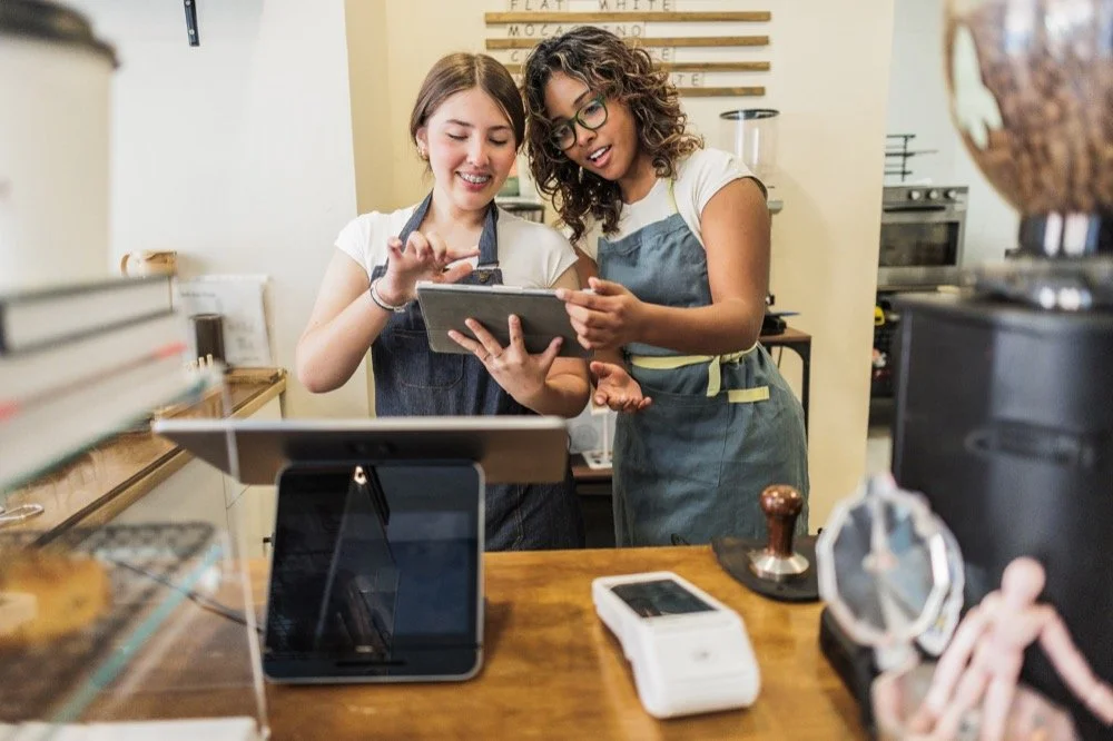 Two small business owners reviewing website content together inside a modern coffee shop in Upland, CA, representing collaboration, digital marketing, and small business web design services.