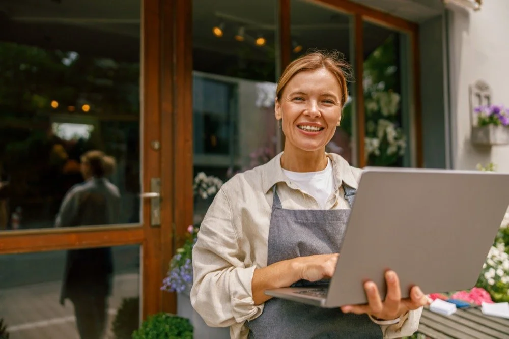 Small business owner working on a laptop outside a storefront, representing strategic branding, brand clarity, and business growth for Inland Empire entrepreneurs.