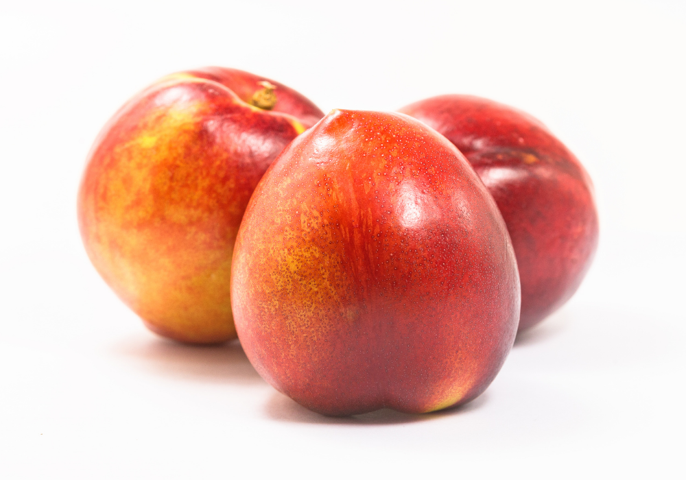 Three red and yellow nectarines on a white background.