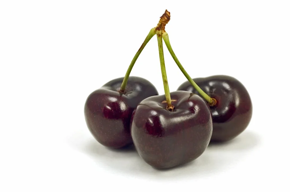 Three dark red cherries with green stems on a white background.