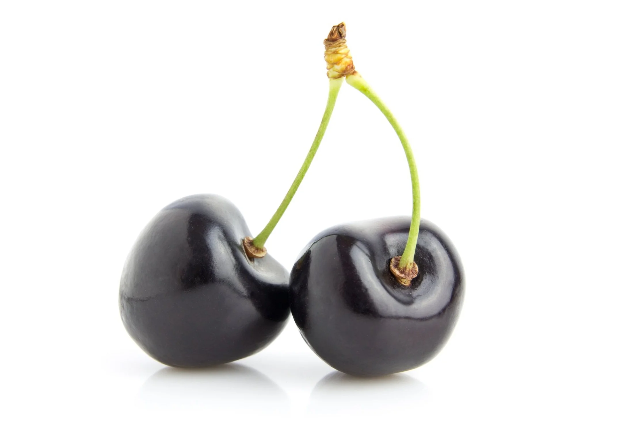 Two black cherries with green stems on a white background.