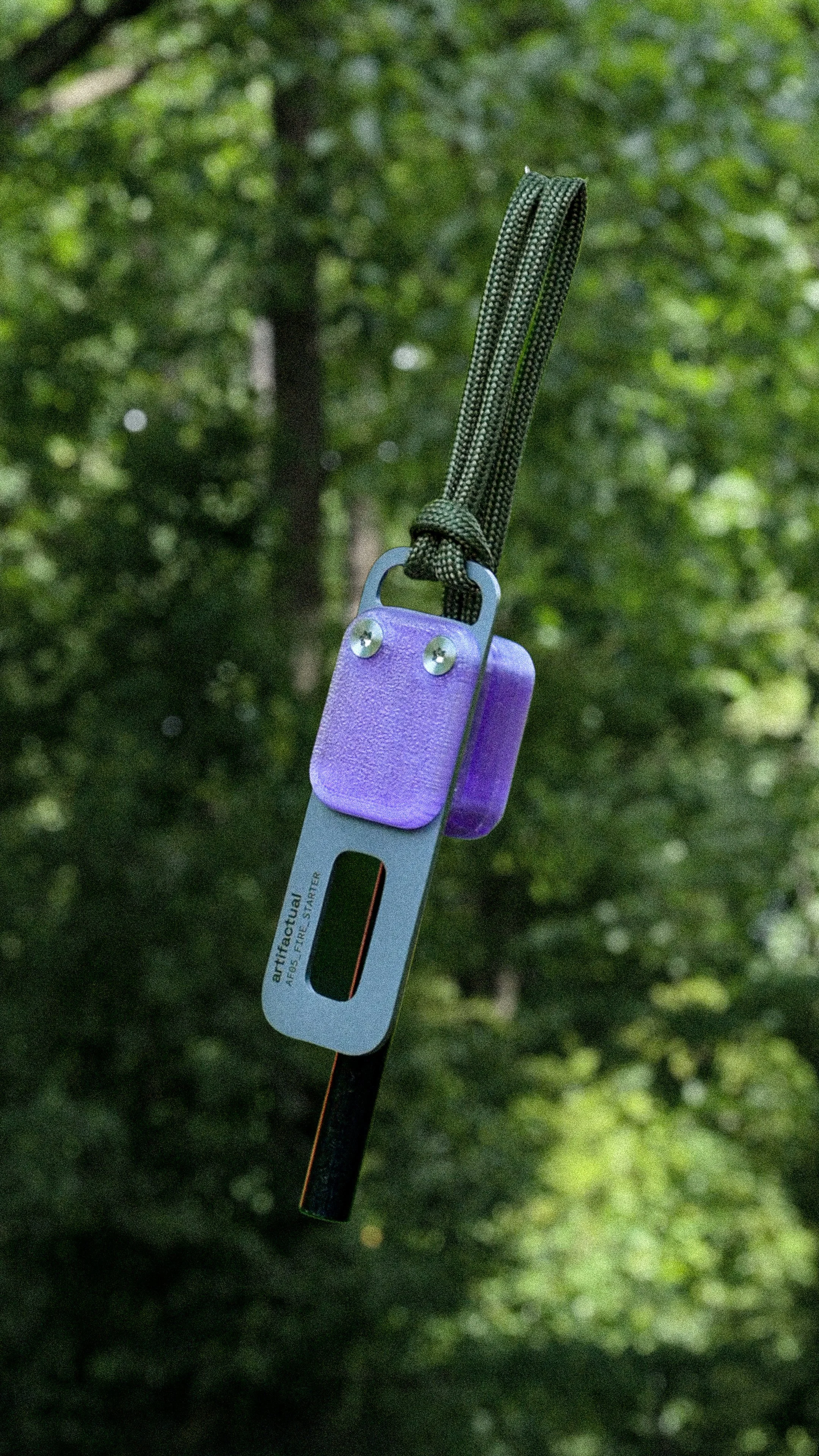 A person holding a metal ice axe with a purple grip and a wrist strap, used for climbing or hiking on ice or rock.