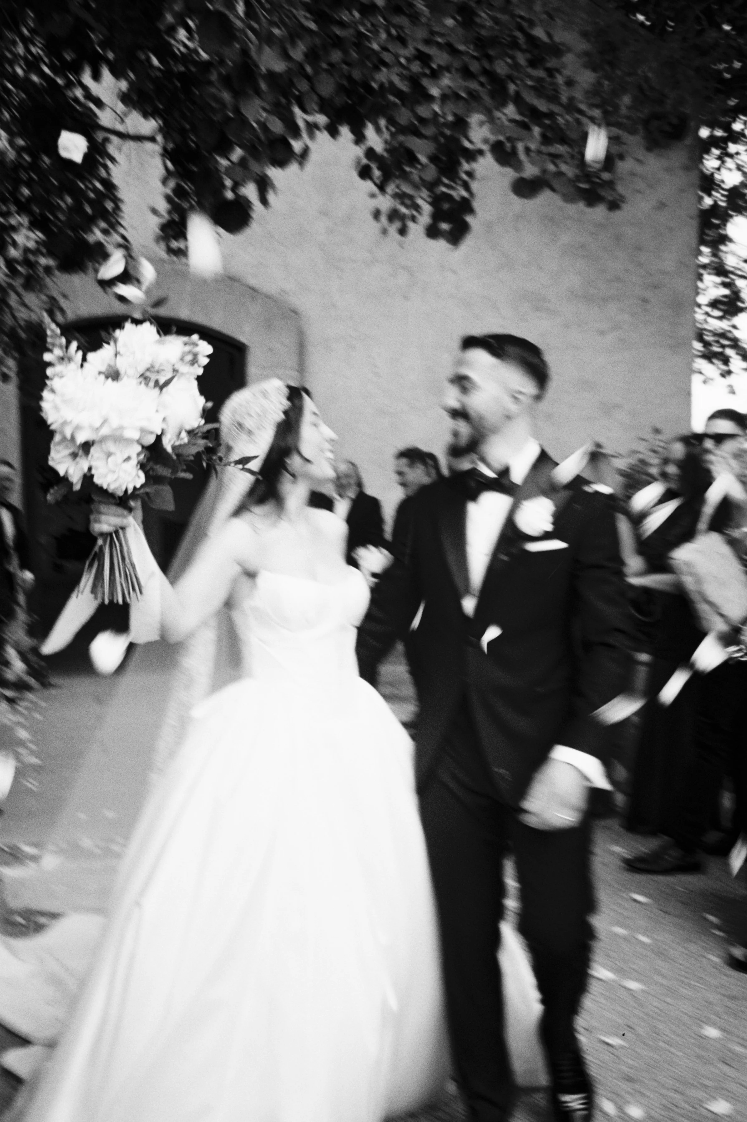 A black and white photo of a bride and groom smiling at each other during their wedding celebration.