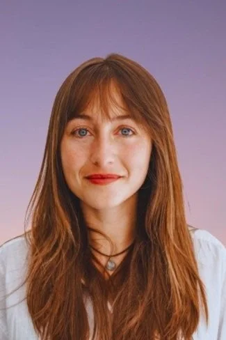 Ritratto di una donna con capelli castani e occhi azzurri, sfondo viola.