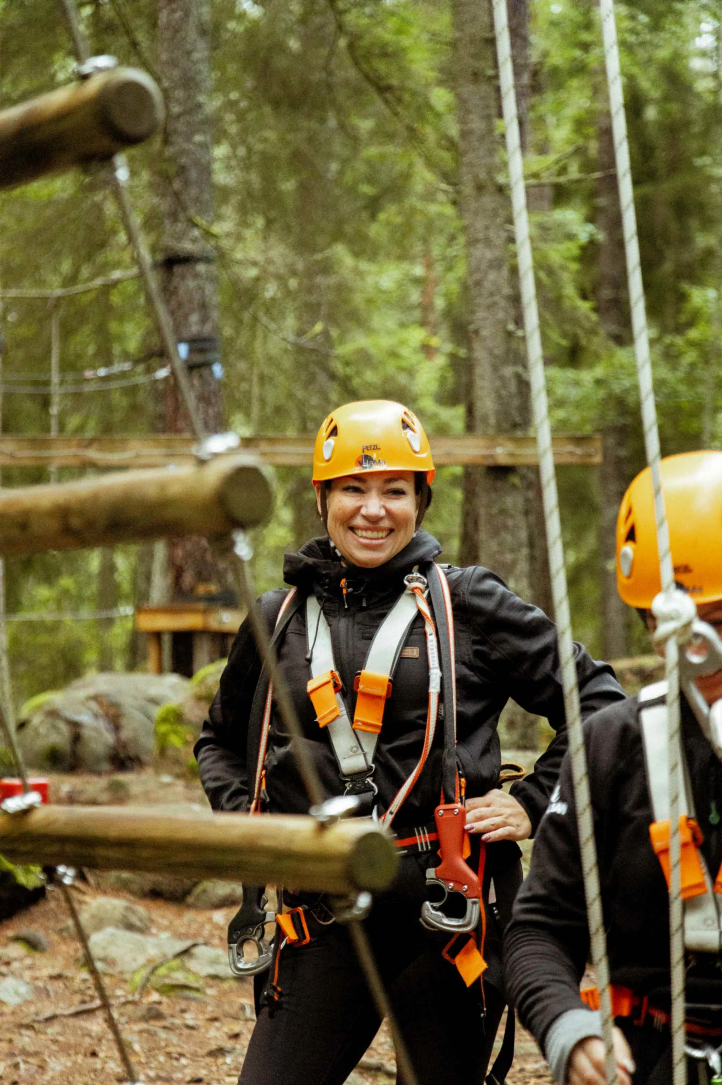 Klättrare med sele och hjälm ler och väntar vid en stege.