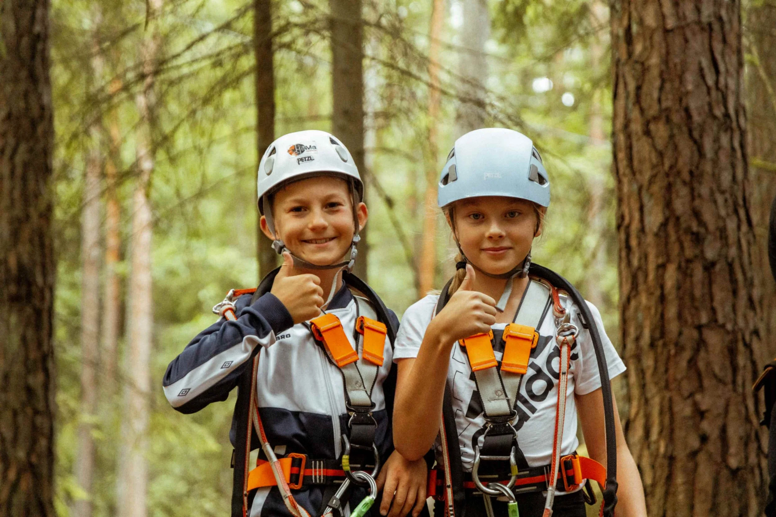 Två barn med klätterutrustning gör tummen upp