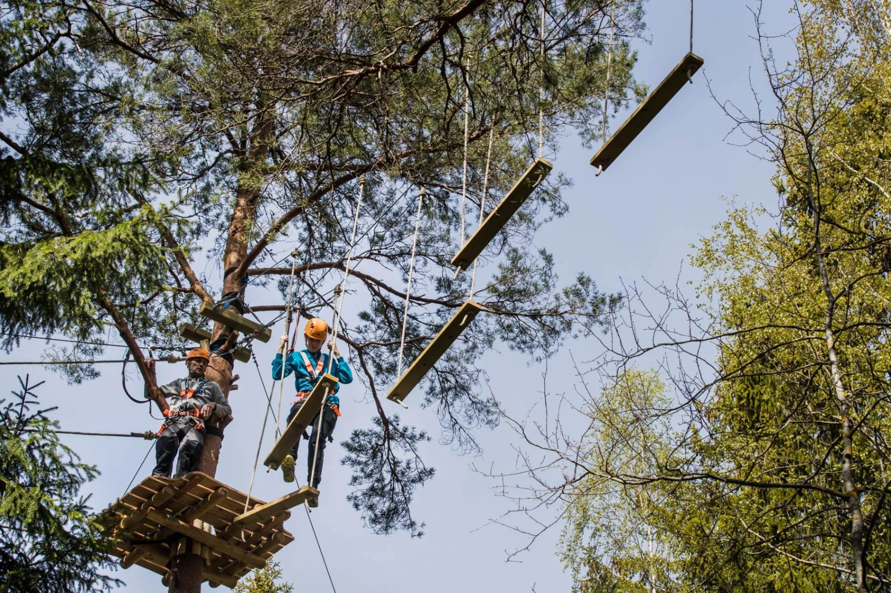 Ung man klättrar på hängande gungor på en hög höghöjdsbana