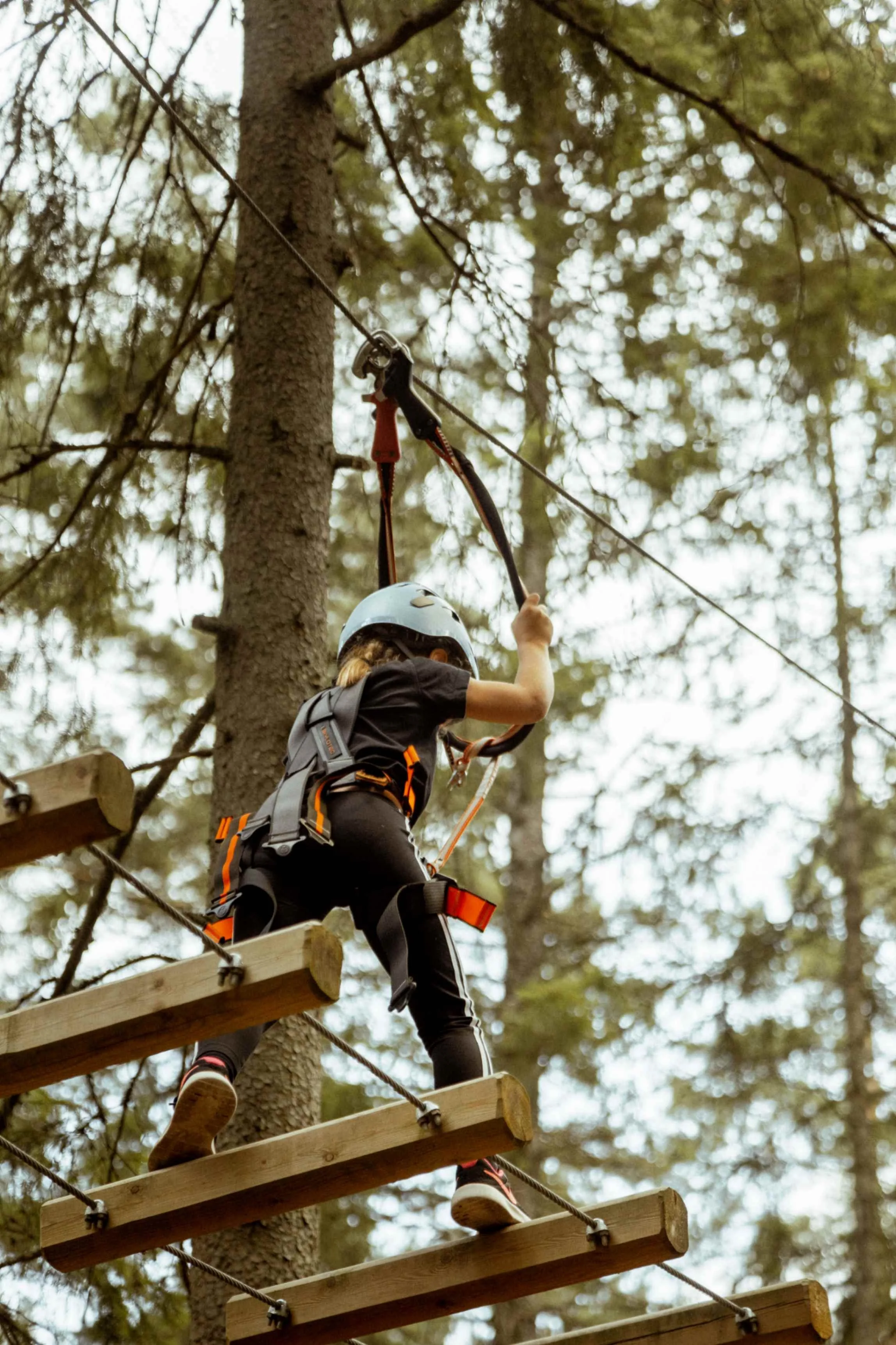 Ung flicka balaserar på en vajerbro på en höghöjdsbana