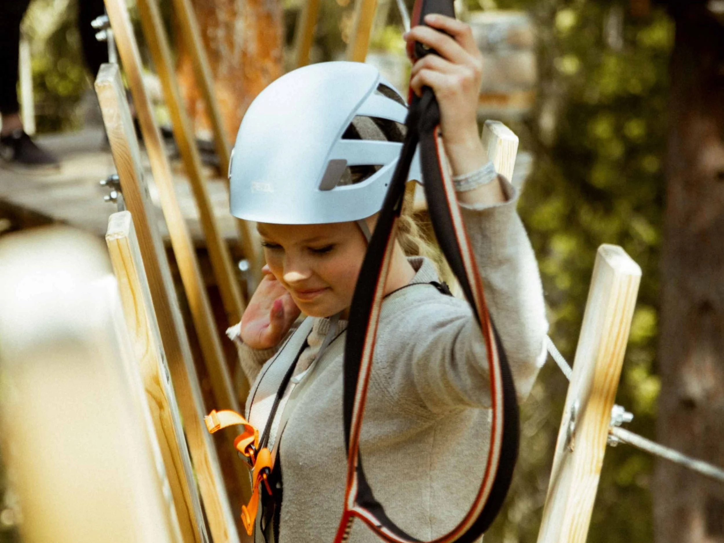 Ung tjej klättrar på höghöjdsbana och håller i säkerhetsutrustningen