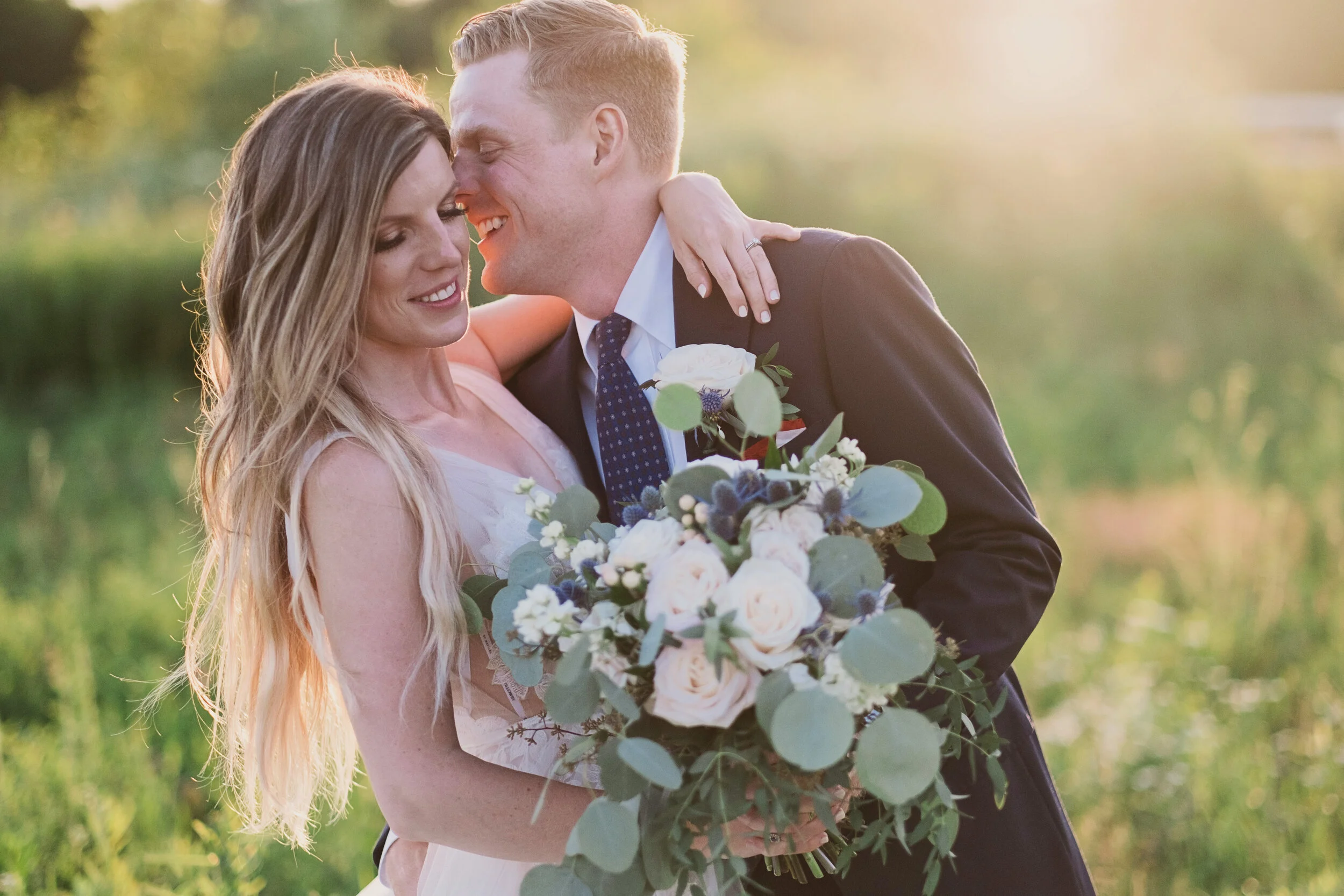 A Hamilton wedding videographer captures a cute wedding couple candidly posing and smiling during their photo session in a farm field in Hamilton, Ontario.