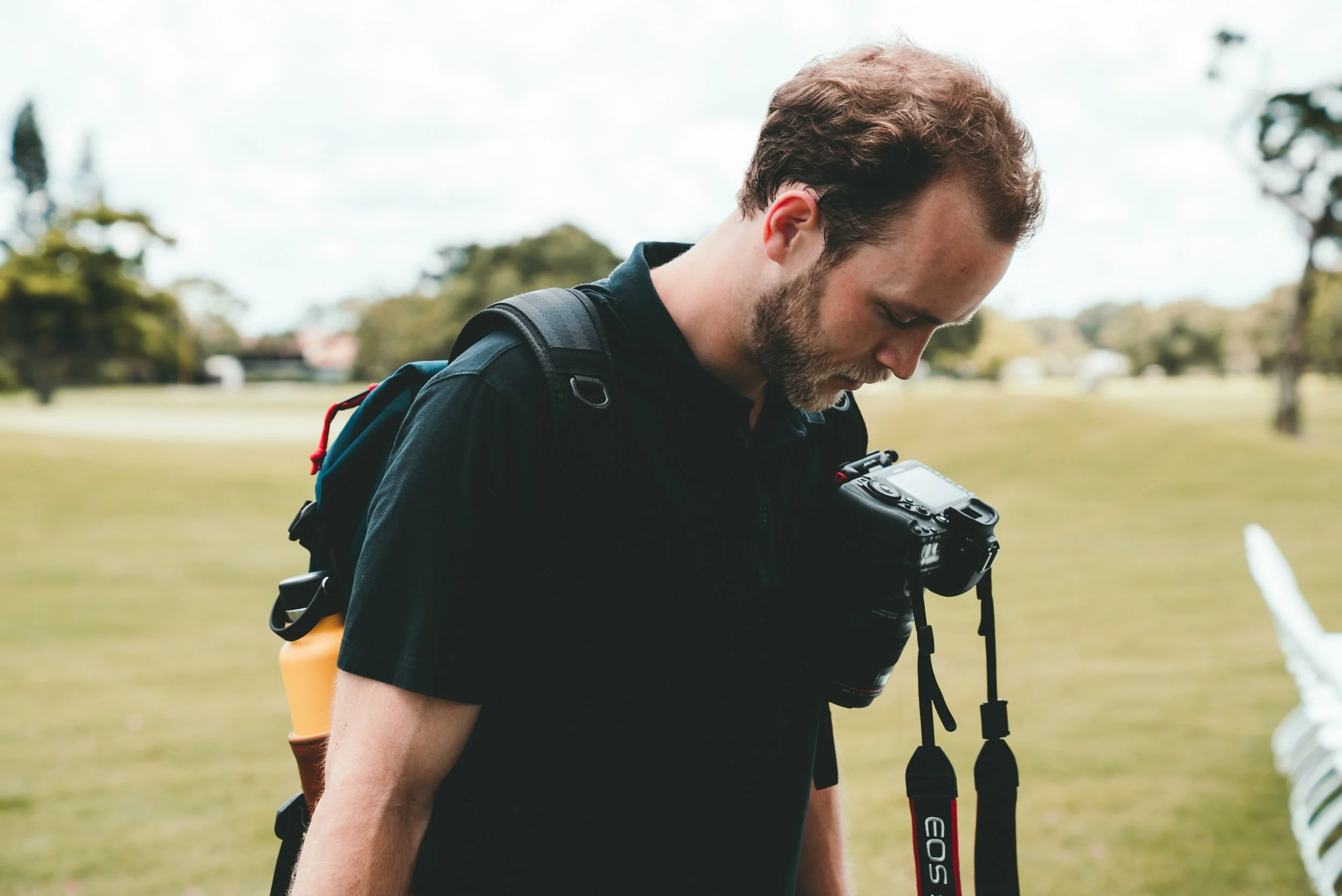 A Toronto wedding videographer looking down at his dslr camera while at a wedding site.