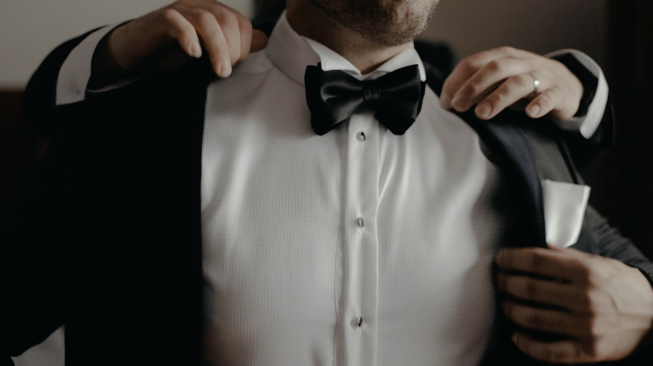 Groom putting on his suit jacket.