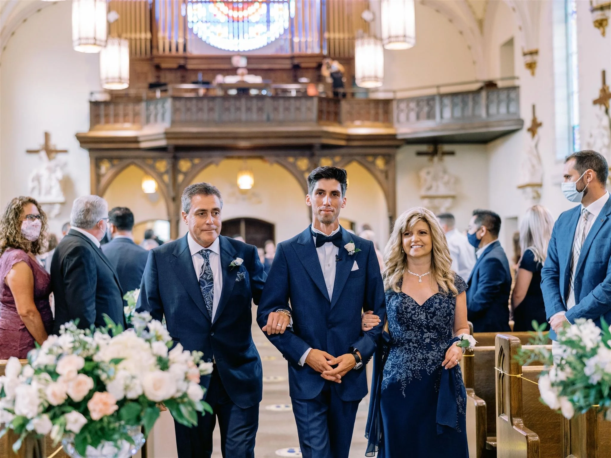 Groom walks down the Church aisle with his parents.
