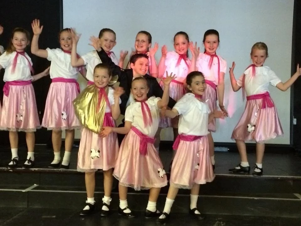 A group of young dancers at Just Dance dressed in 1950s-inspired outfits, smiling and performing a lively and colourful routine.