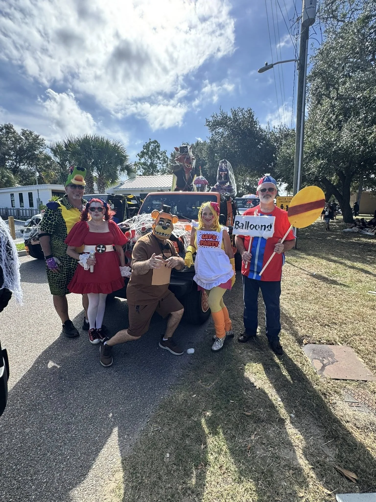 Group of people dressed in Halloween costumes posing outdoors during daytime.